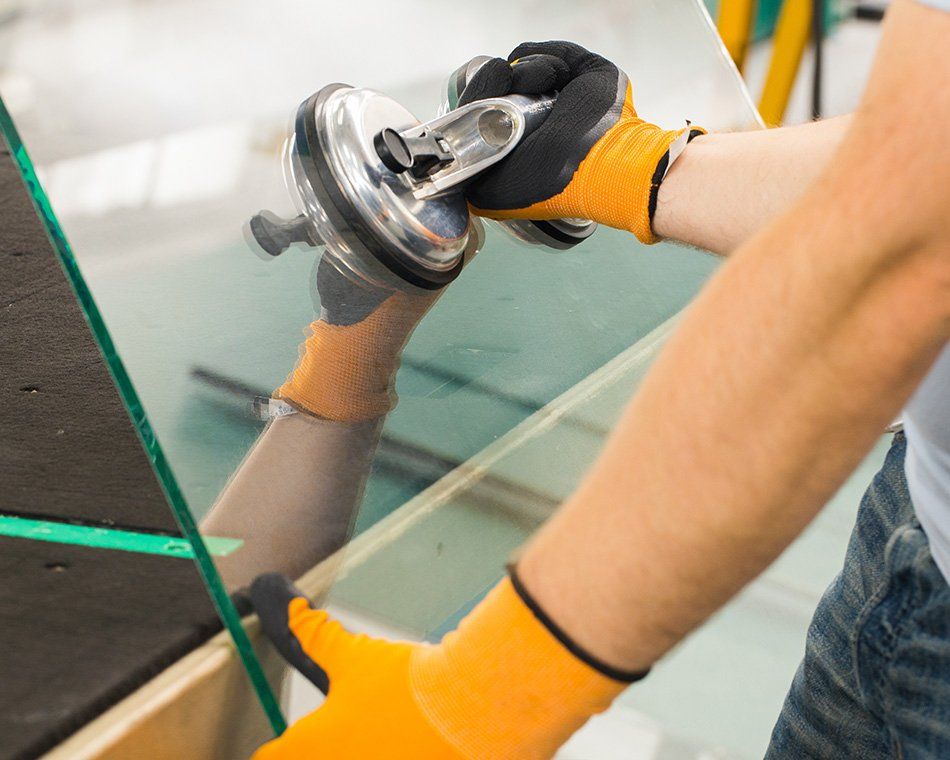 Ouvrier portant une vitre en verre à l'aide d'une ventouse de portage
