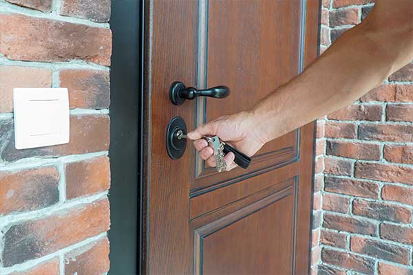 Homme insère une clé dans une serrure de porte en bois