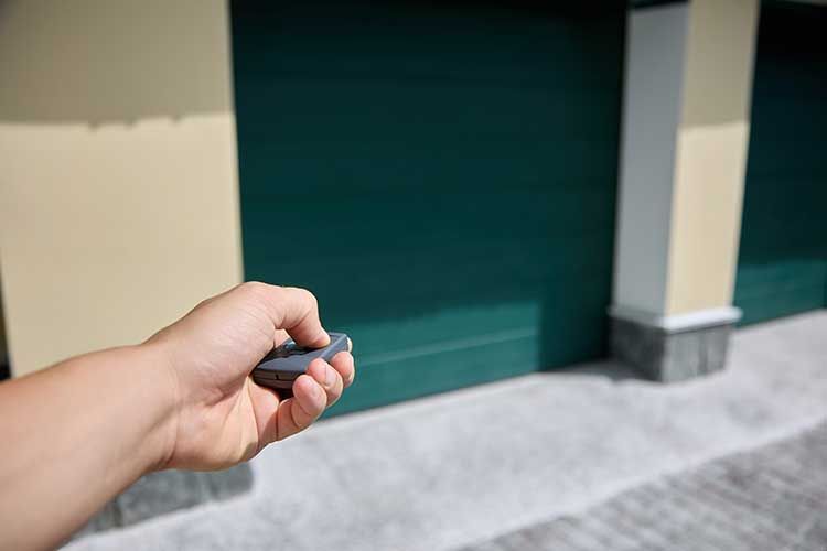 Une main utilise une télécommande d'une porte de garage
