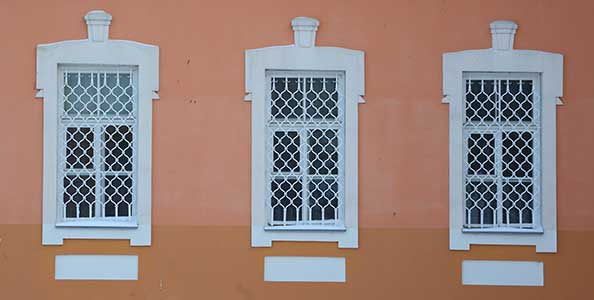 Trois fenêtres blanches avec des grilles de défense