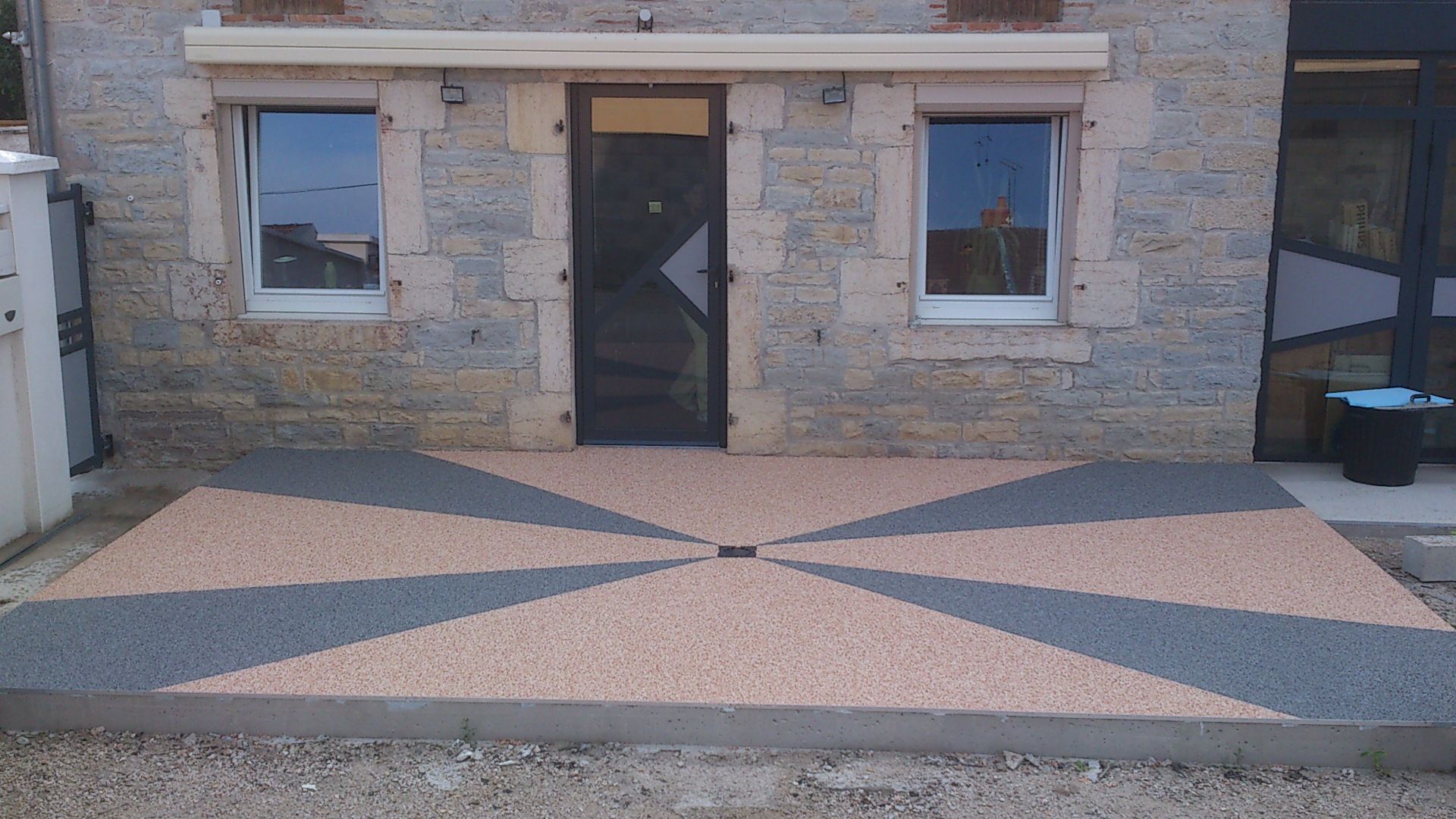 Bâtiment en pierre avec une terrasse pavée colorée en forme d'étoile.