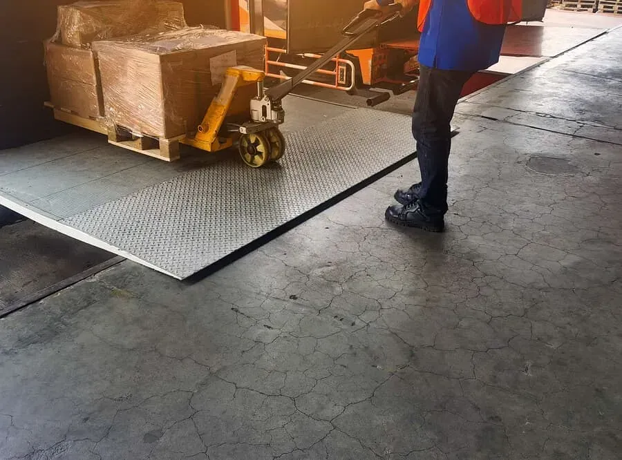 Un hombre está de pie junto a una transpaleta en un almacén.