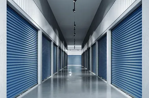 Un largo pasillo lleno de filas de puertas de garaje azules.