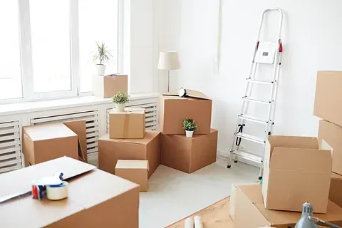 Una sala de estar llena de cajas de cartón y una escalera.
