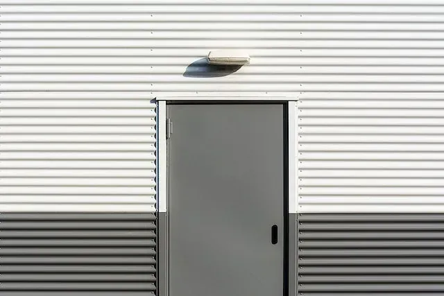 Una puerta gris está en el costado de un edificio.
