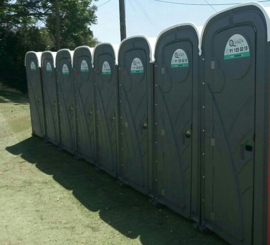 Una fila de baños portátiles están alineados en un campo