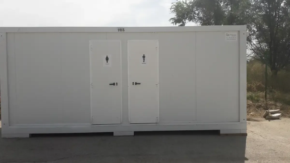 Un edificio blanco con dos puertas está situado encima de un camino de tierra.