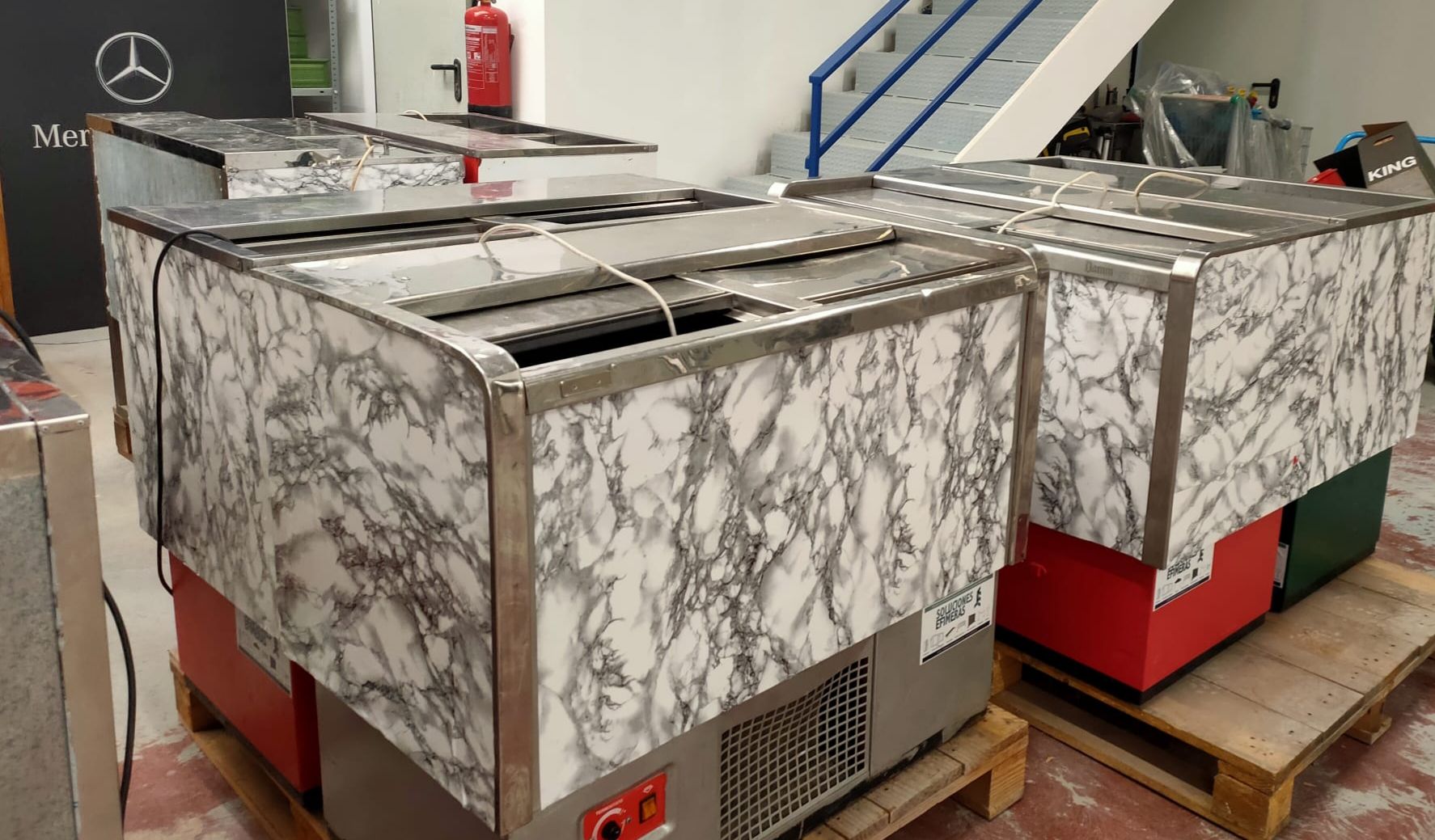 Un grupo de refrigeradores están colocados encima de una paleta de madera.