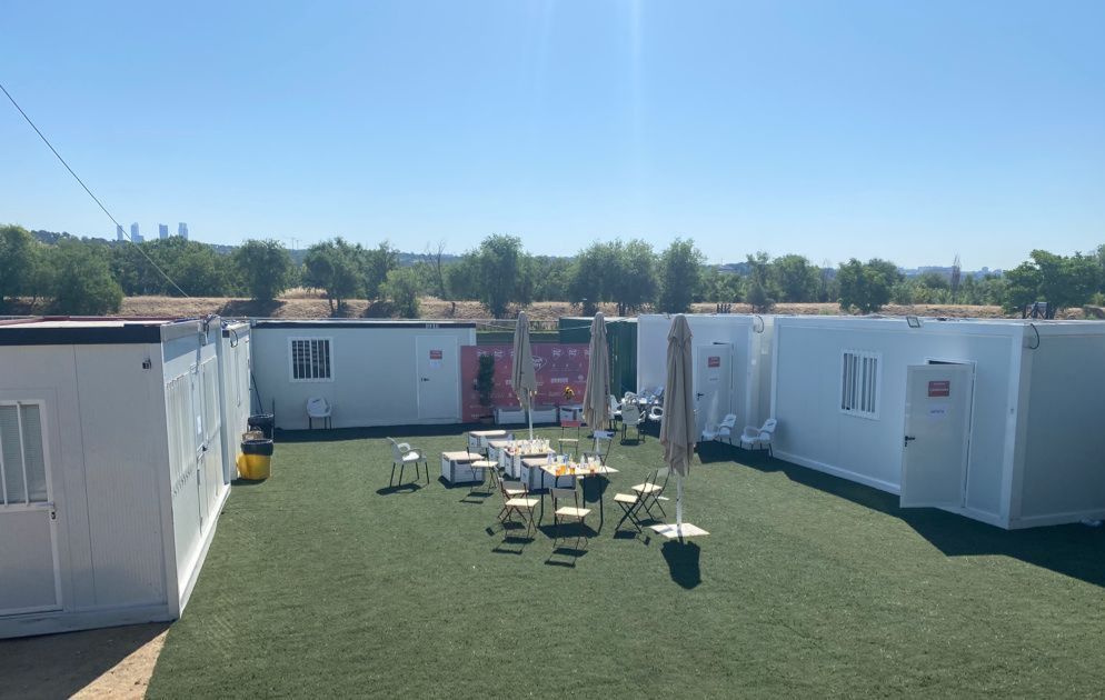 Un grupo de edificios blancos se encuentran sobre un exuberante campo verde.