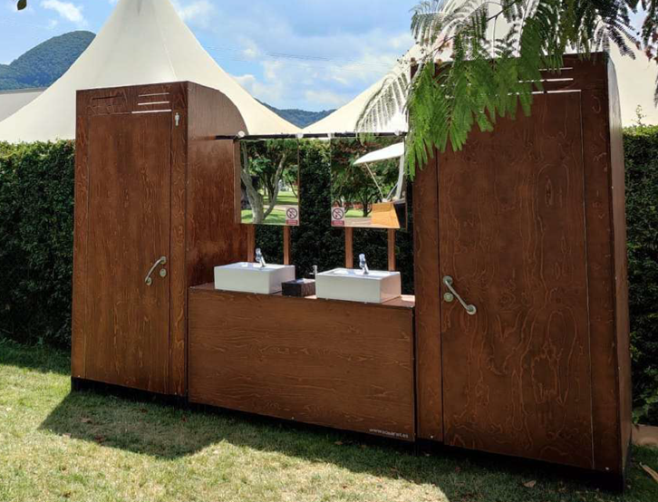 Un baño de madera con dos lavabos y dos espejos en un campo.