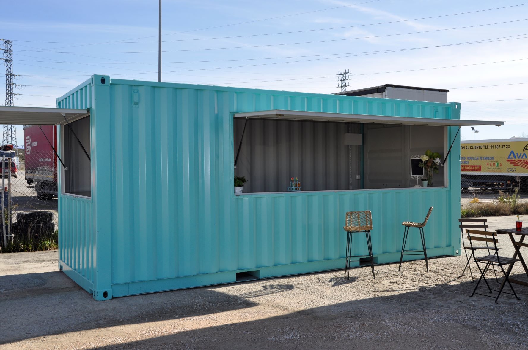 Un contenedor de envío azul con una mesa y sillas delante de él.