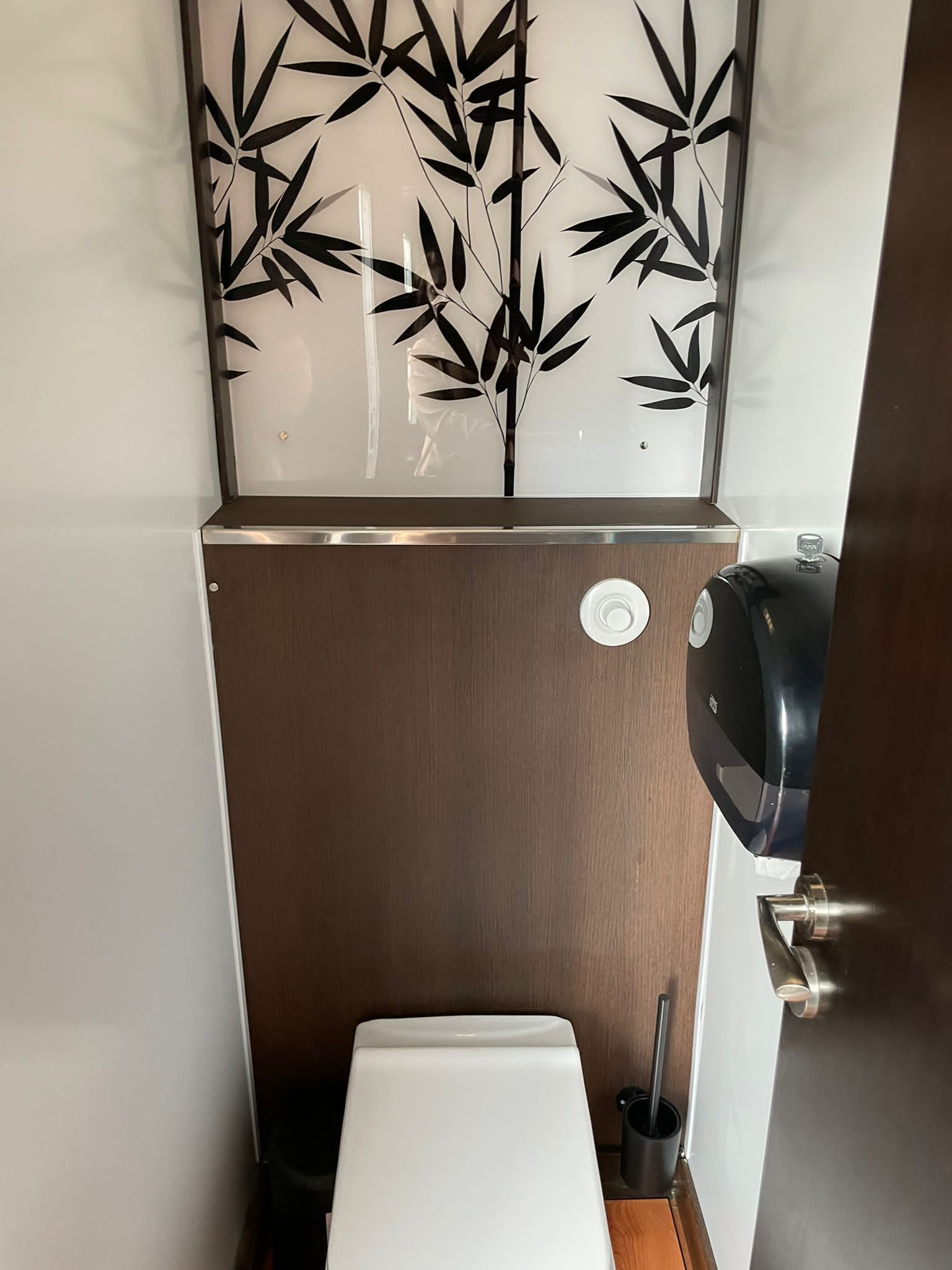 Un baño con inodoro y dispensador de toallas de papel.