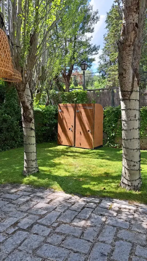 Una caja de madera se encuentra en medio de un exuberante campo verde rodeado de árboles.