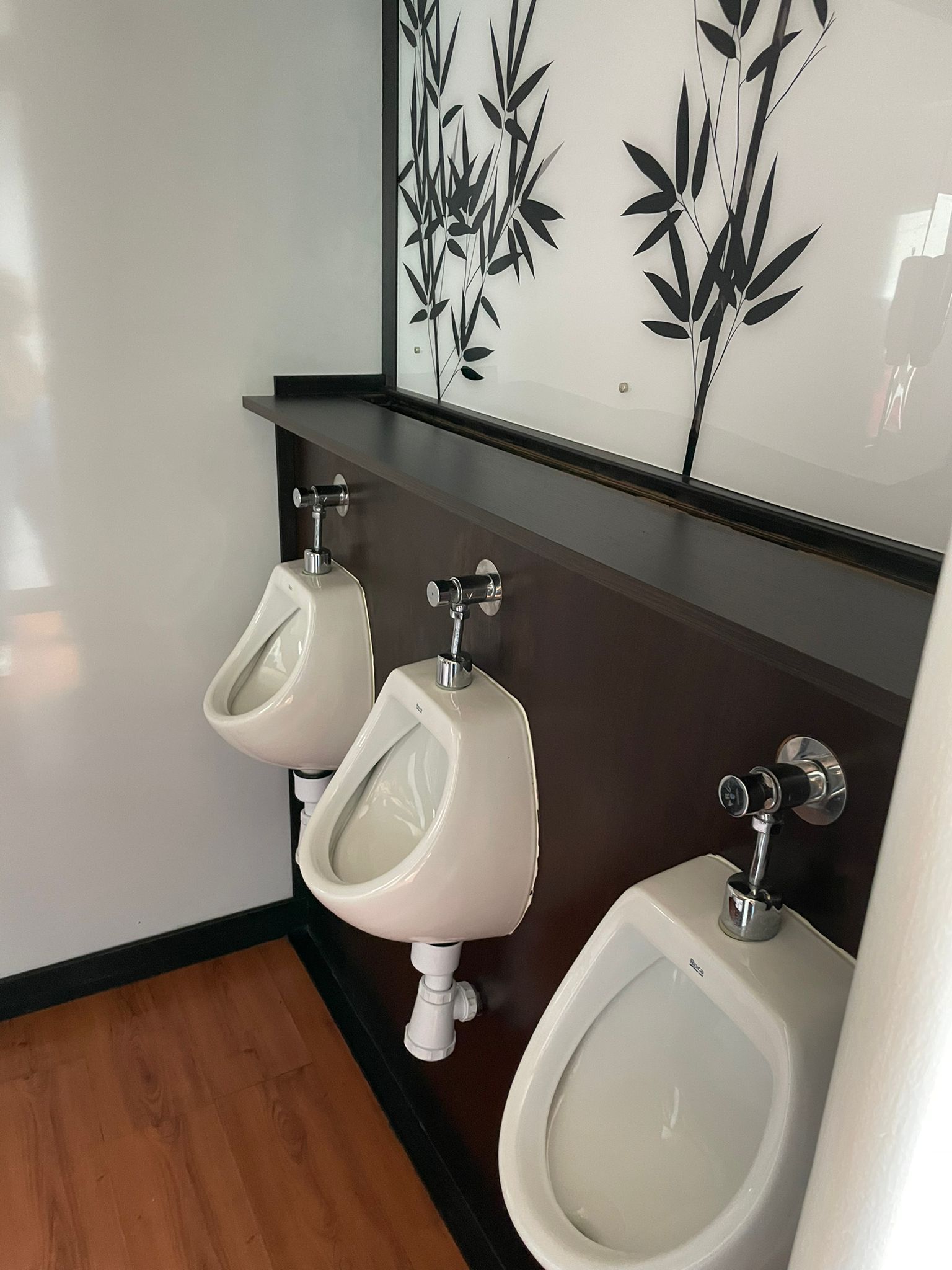 Tres urinarios están alineados en un baño público.
