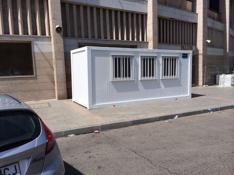 Un coche está aparcado delante de un edificio blanco con rejas en las ventanas.