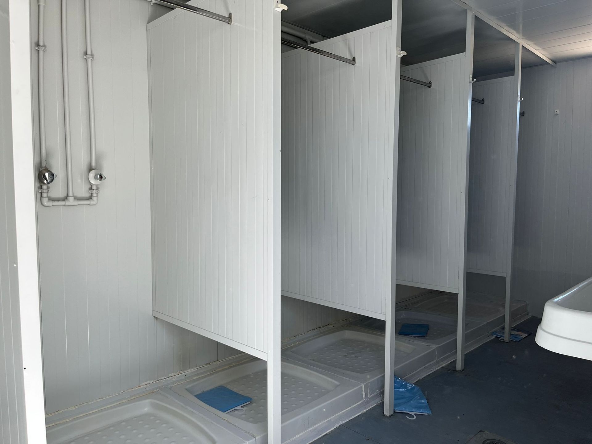 Un baño con una fila de duchas y un lavabo.