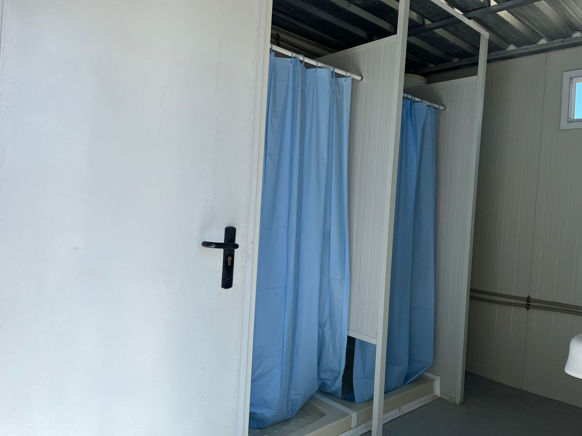 Una fila de cabinas de ducha con cortinas azules en un baño.