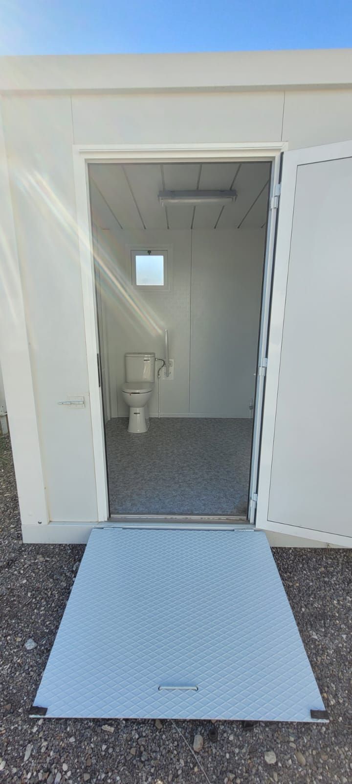 Un baño con inodoro y una rampa que conduce al mismo.