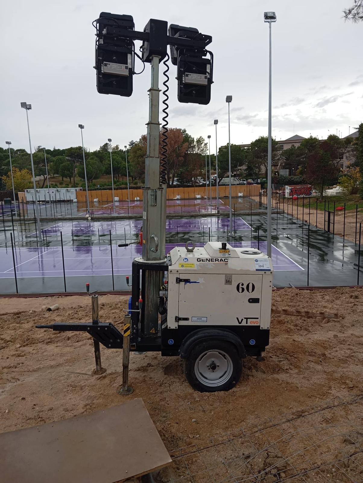 Un remolque con dos luces está estacionado frente a una cancha de tenis.