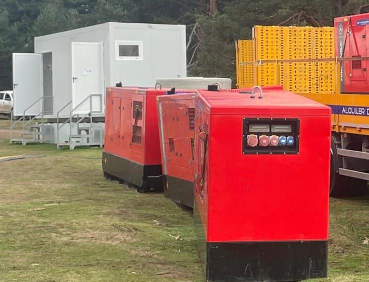 Una fila de generadores rojos están estacionados en un campo de hierba.