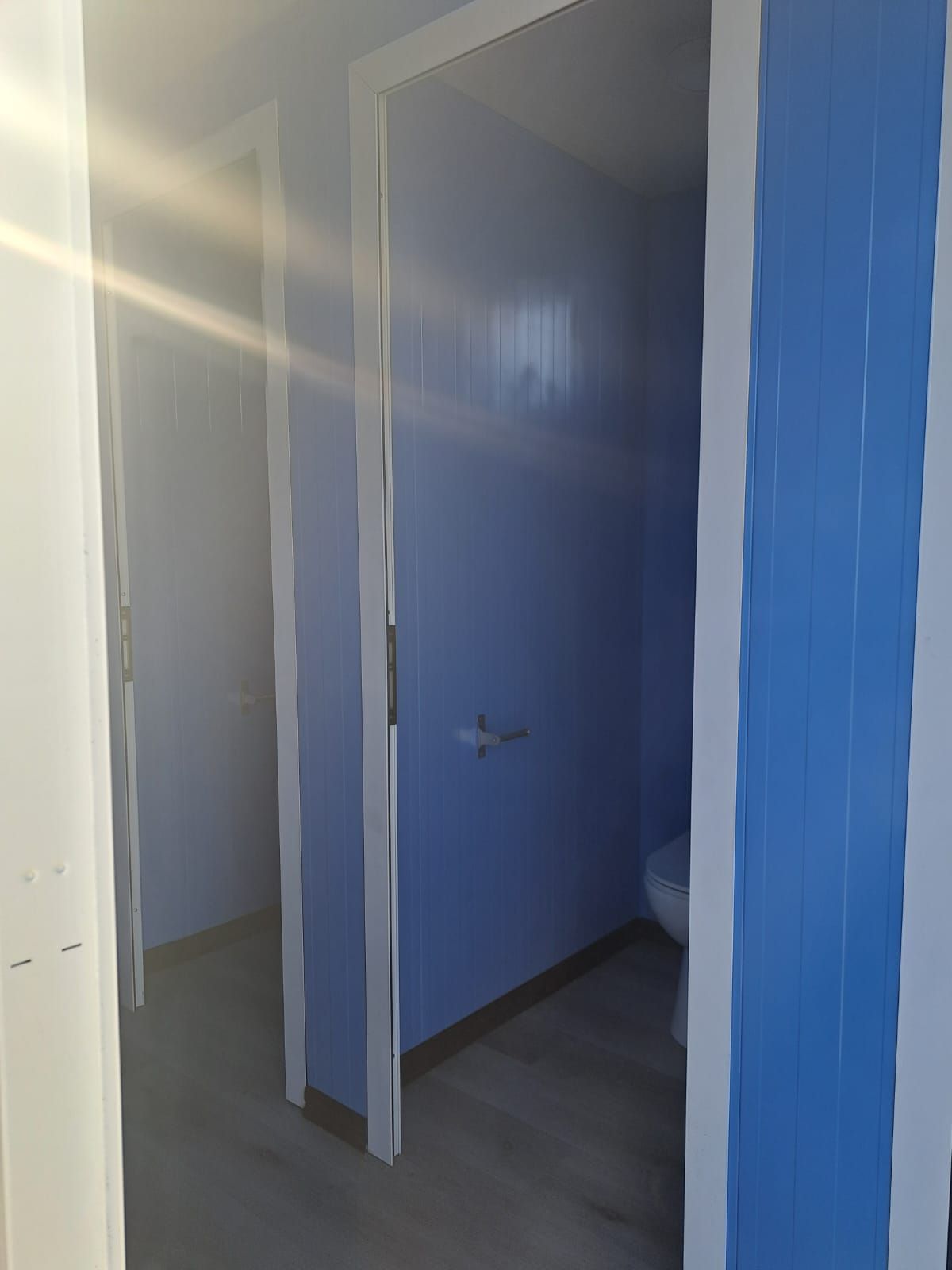 Un baño con paredes azules y molduras blancas y un inodoro.