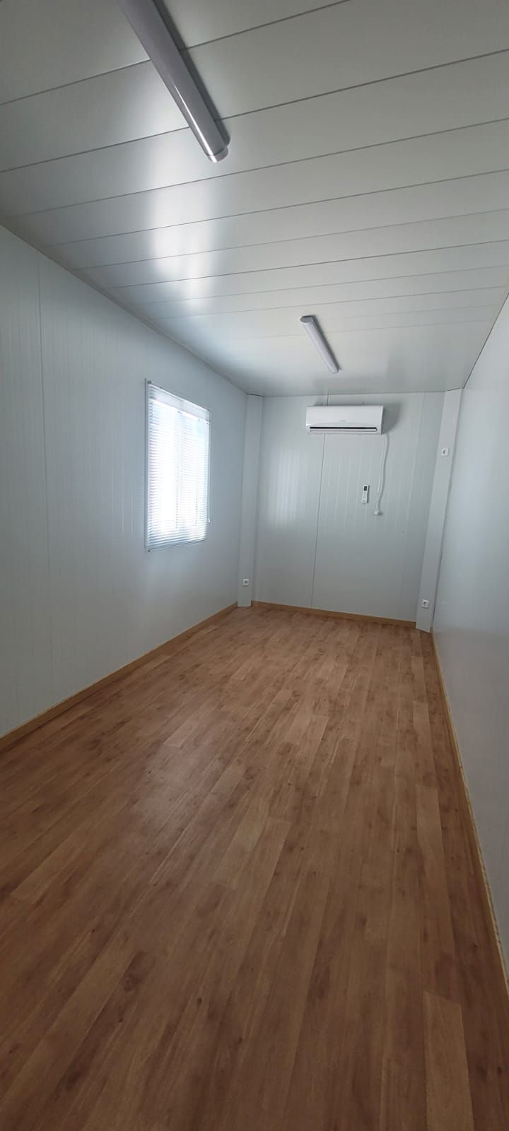Una habitación vacía con suelos de madera y paredes blancas.