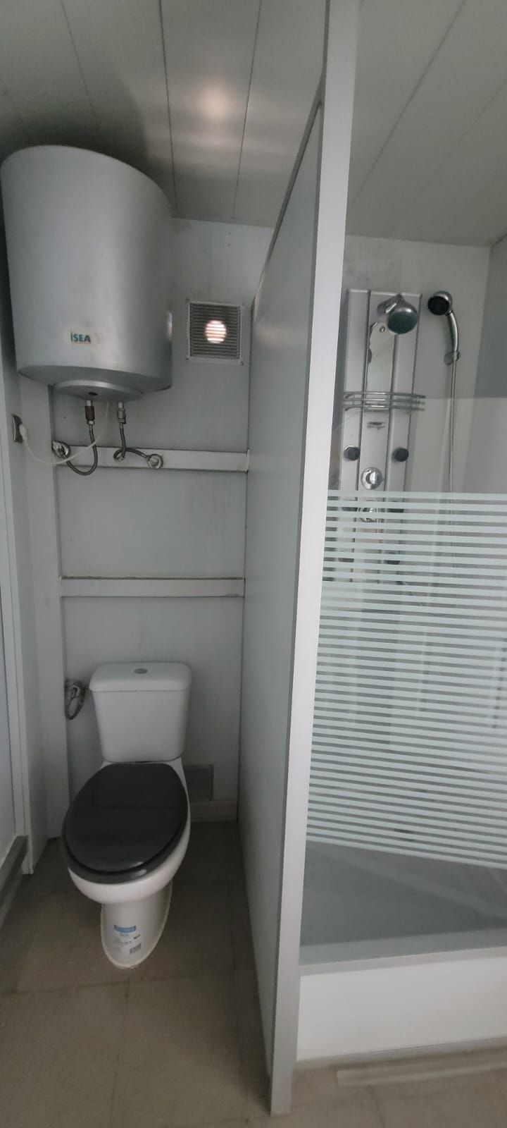 Un baño con inodoro, calentador y ducha.