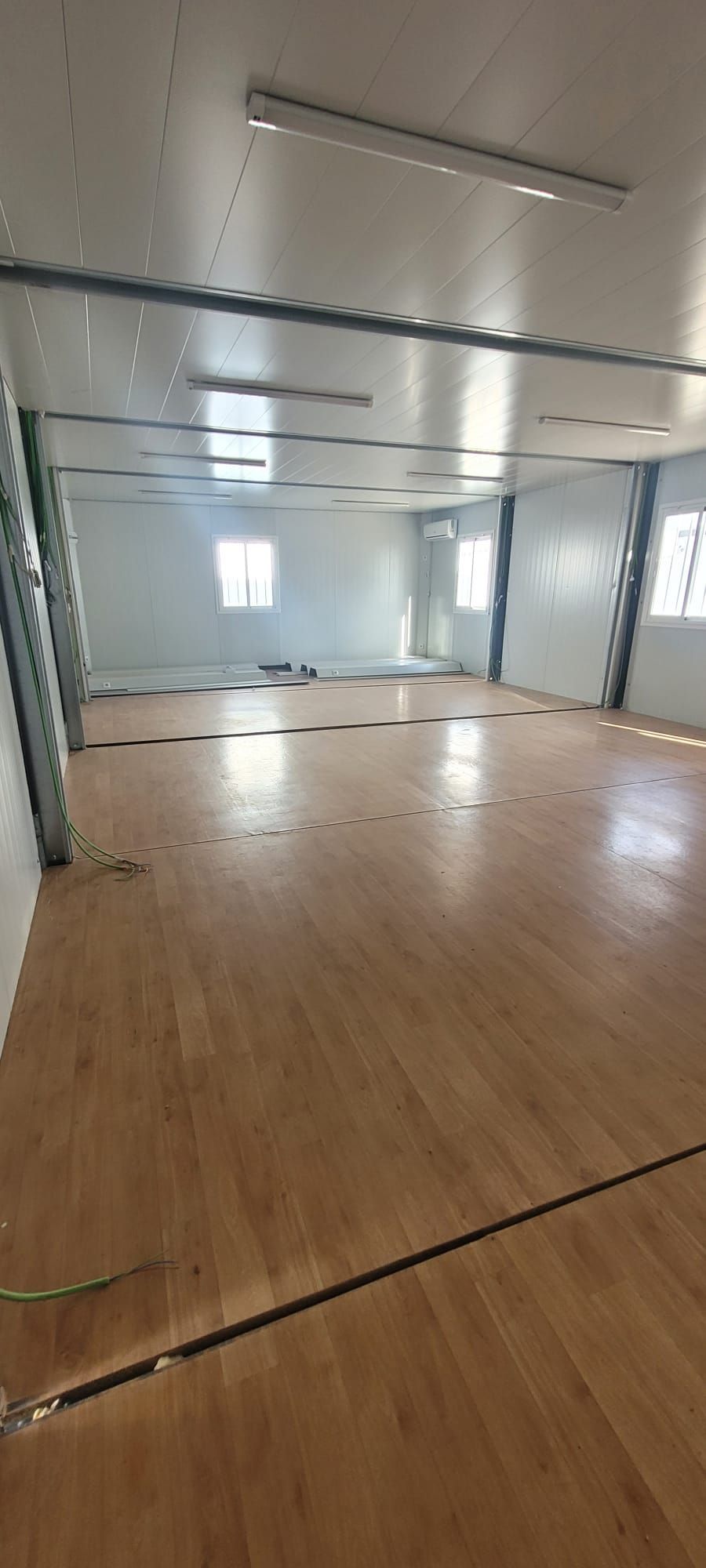 Una gran habitación vacía con suelo de madera y paredes blancas.