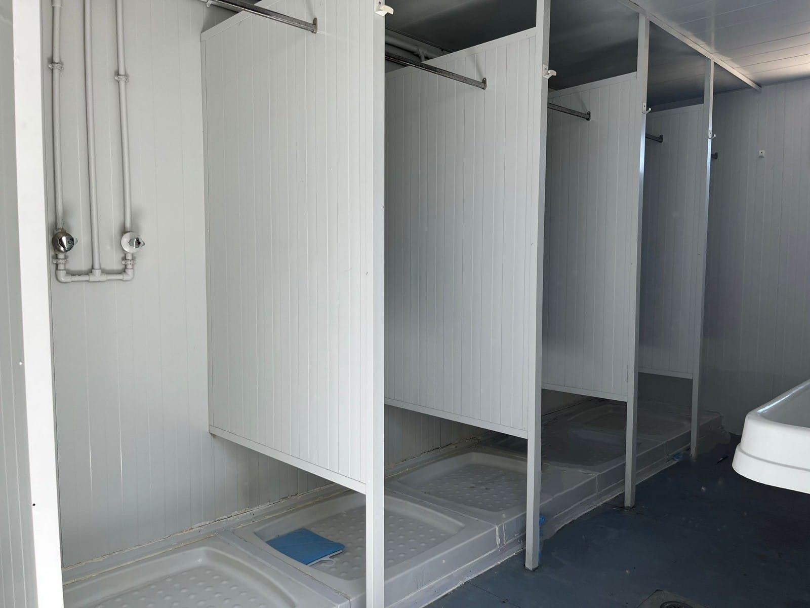 Un baño con una fila de duchas y un lavabo.