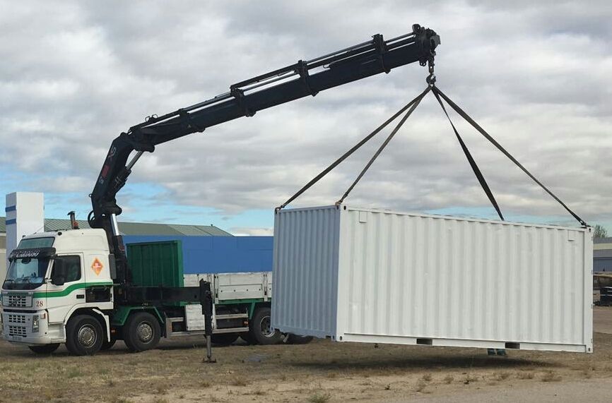 Un camión con una grúa levantando un contenedor de envío