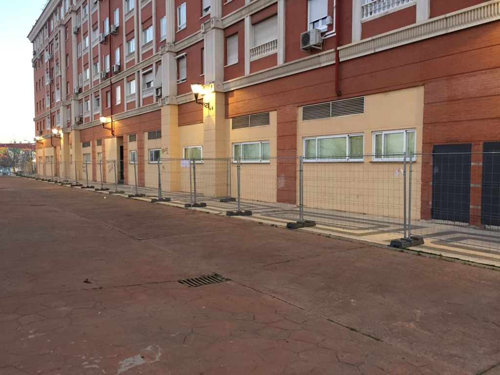 Un edificio con muchas ventanas y una valla alrededor.