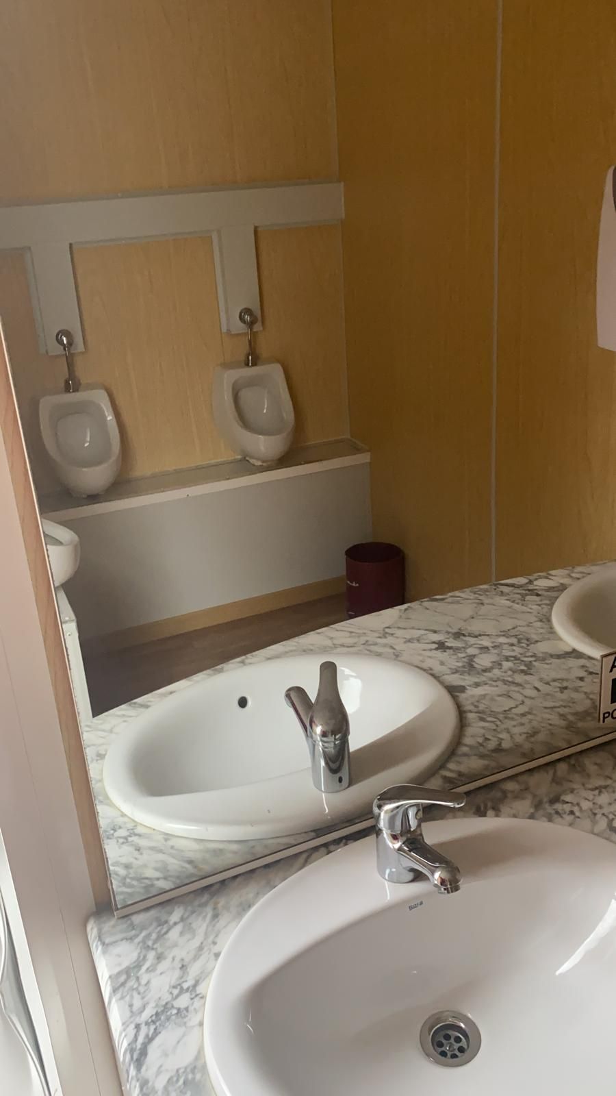 Un baño con dos lavabos, dos urinarios y un espejo.