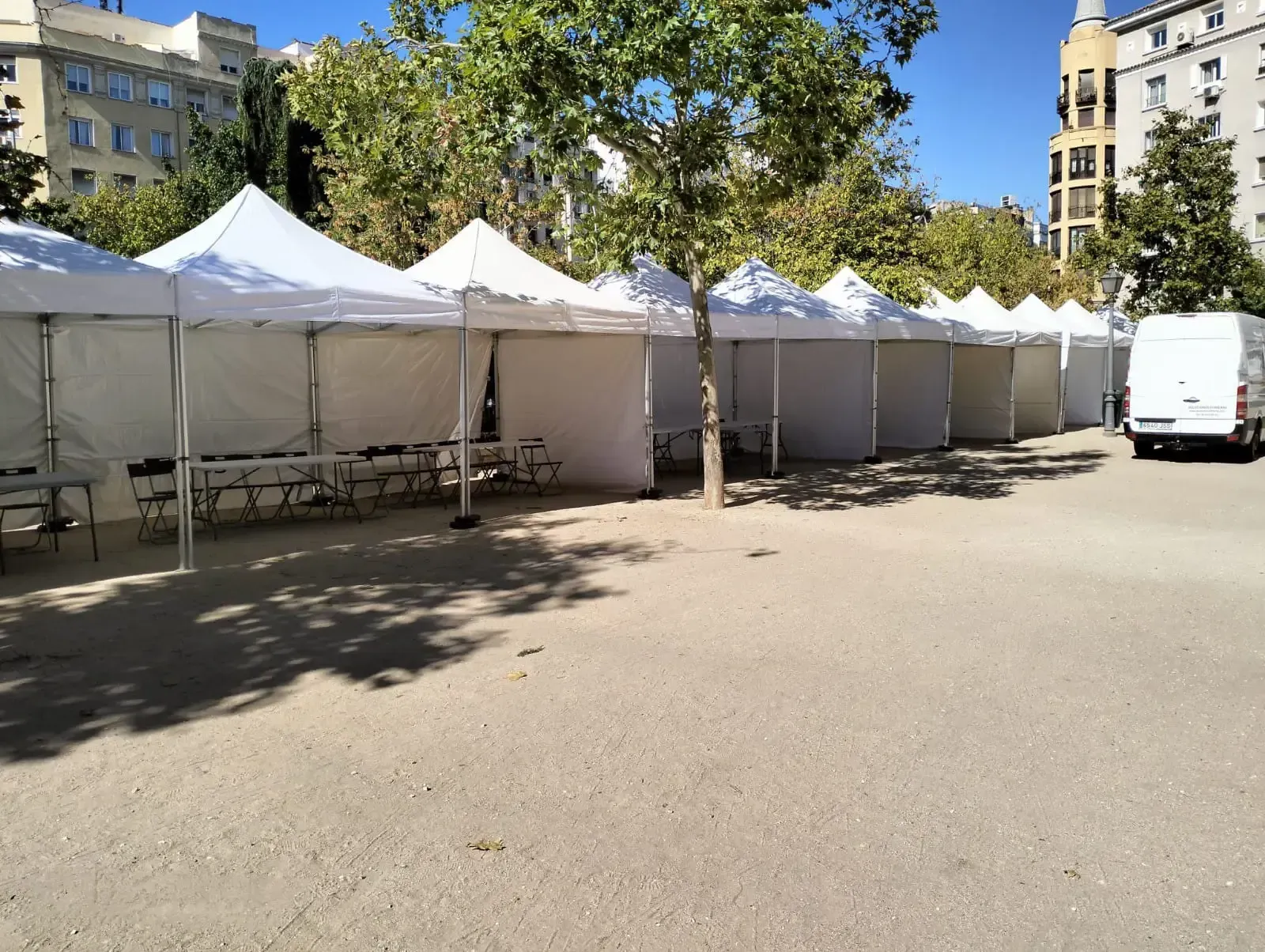 Una fila de carpas blancas están alineadas en un estacionamiento