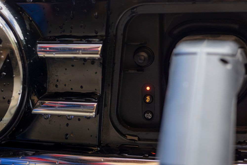 Ladeanschluss für Elektrofahrzeuge mit leuchtender orangefarbener Kontrollleuchte und eingestecktem Ladekabel.