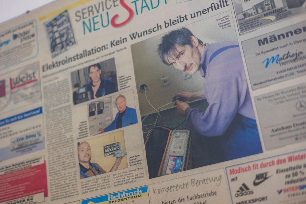 Zeitungsartikel über Elektroarbeiten; Elektriker arbeitet an Kabeln, mit weiteren Porträtaufnahmen.