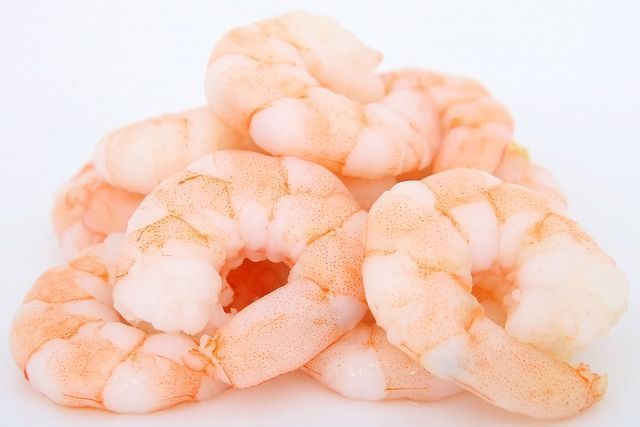 Un montón de camarones cocidos sobre una superficie blanca.