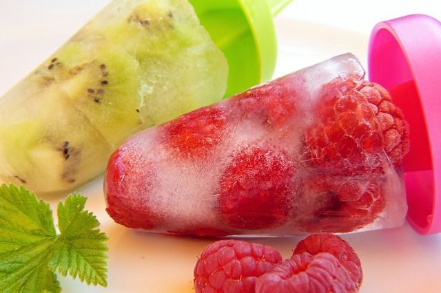 Un primer plano de una paleta de kiwi y frambuesa sobre una mesa.