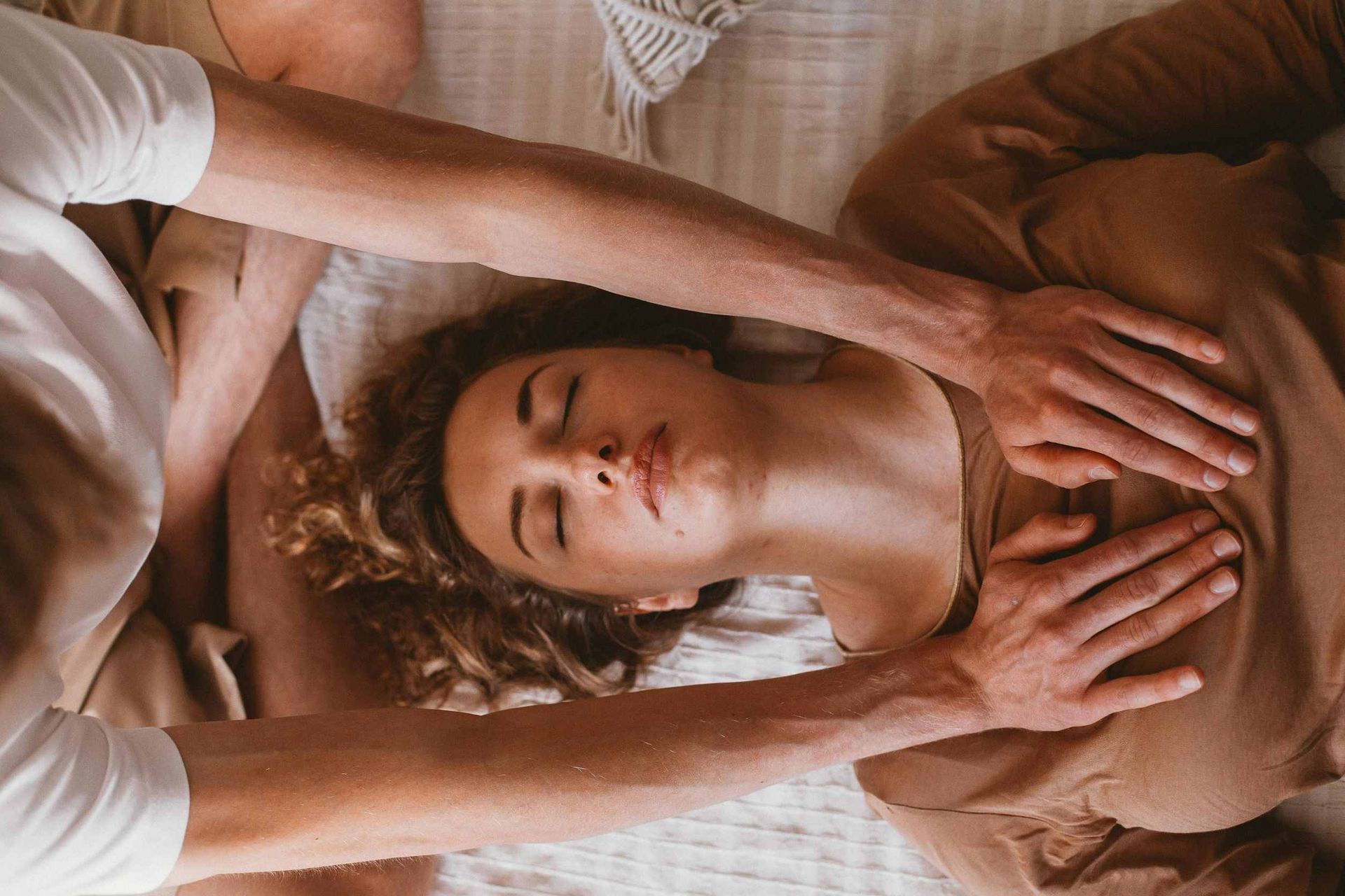 Una mujer está acostada en una cama recibiendo un masaje de un hombre.