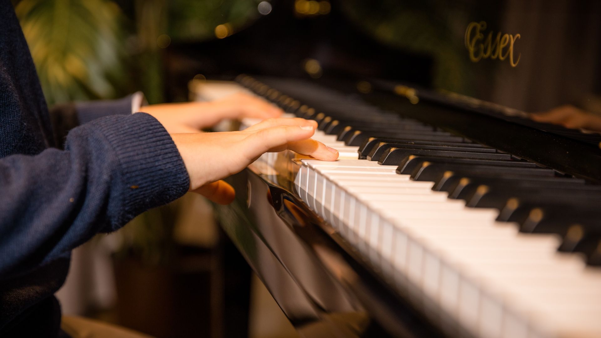 Kinderhände auf den Tasten eines Essex-Klaviers bei Piano Metz by DAUM