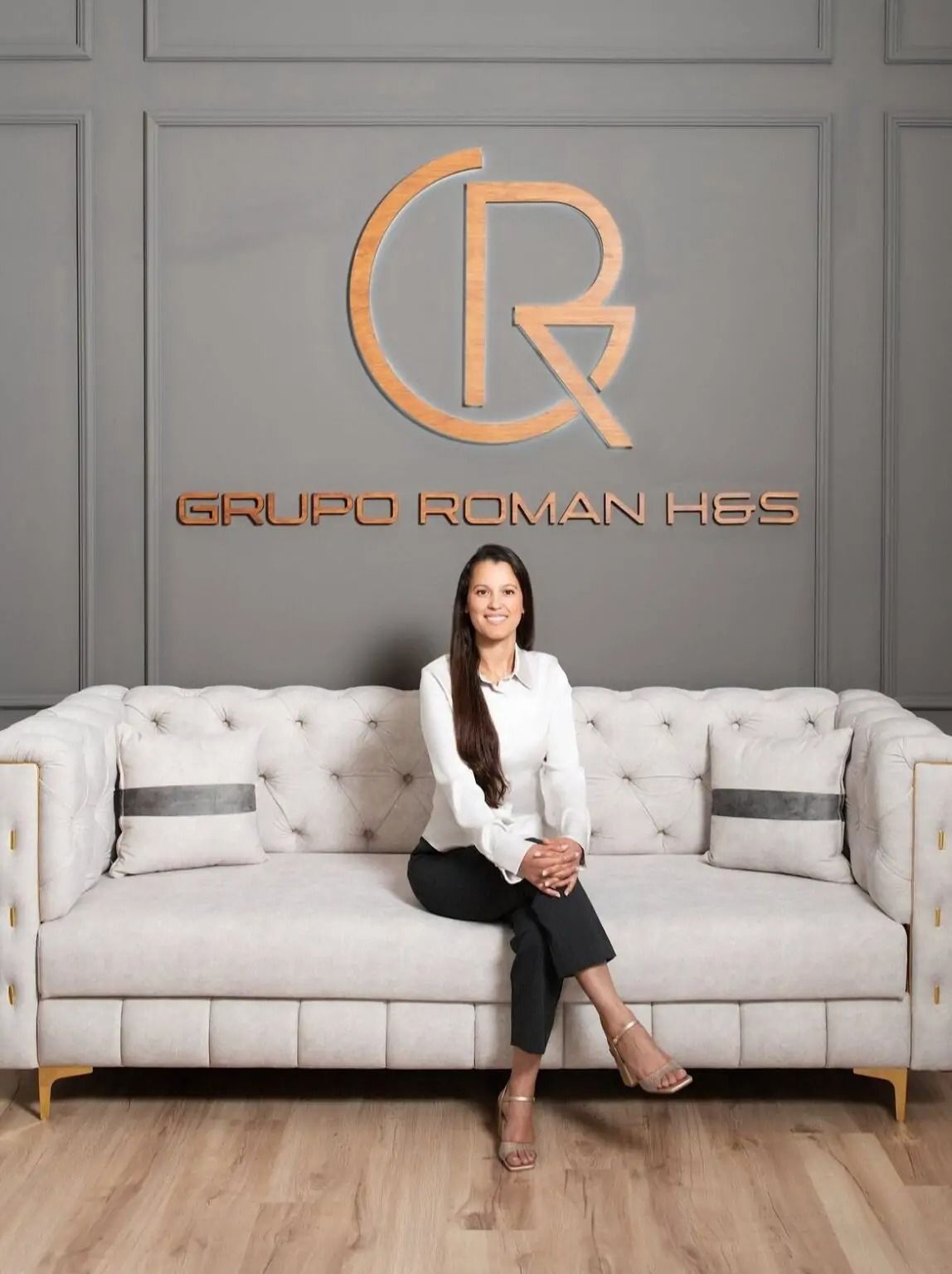 Mujer sentada en un sofá capitoné en un vestíbulo moderno con un gran logotipo dorado