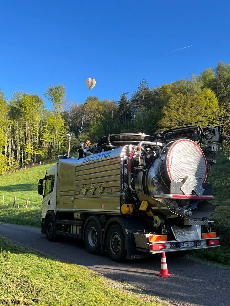 camion MBJ assainissement sur la route avec une montgolfière en arrière plan 