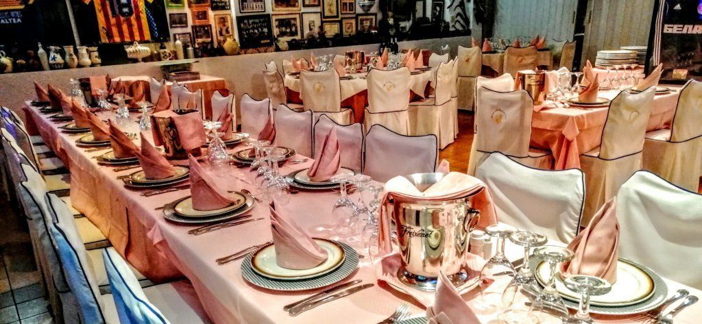Una mesa larga con platos, vasos y servilletas sobre ella.