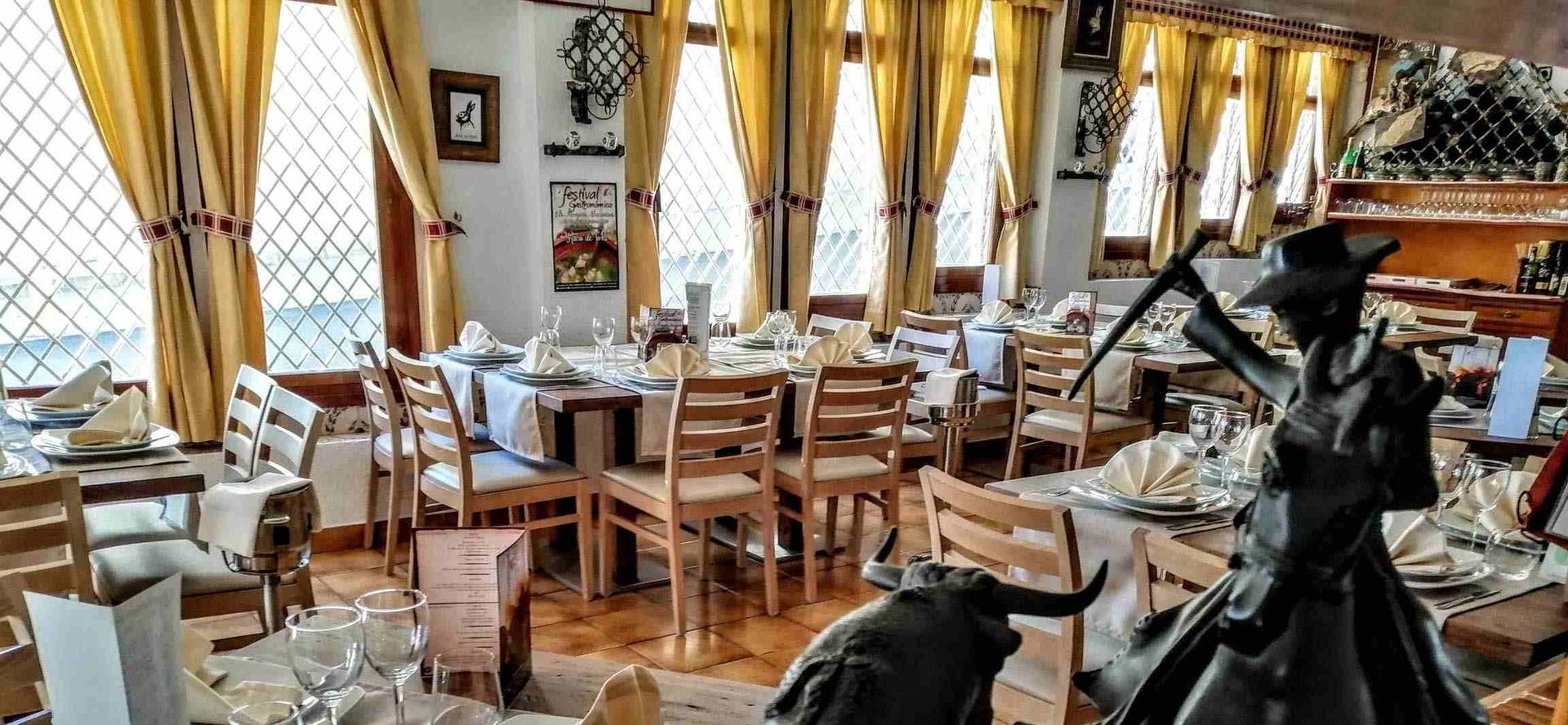 Un restaurante con mesas y sillas y una estatua de una mujer y un toro.