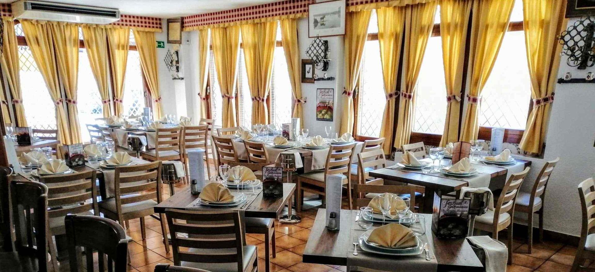 Un gran comedor lleno de mesas y sillas y cortinas amarillas.
