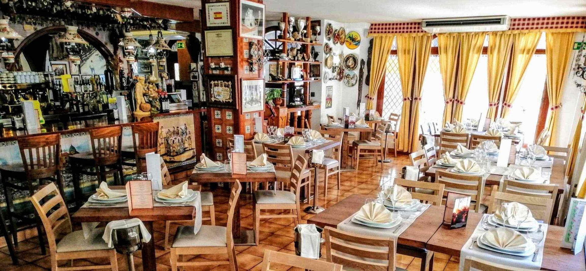 Un restaurante lleno de mesas y sillas y platos sobre ellas.