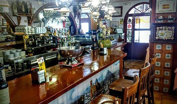 Un restaurante con una larga barra de madera y taburetes.