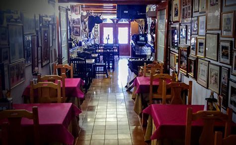 Un restaurante con mesas y sillas y cuadros en la pared.