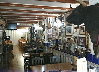 Un restaurante con mesas y sillas y una cabeza de toro en la pared.