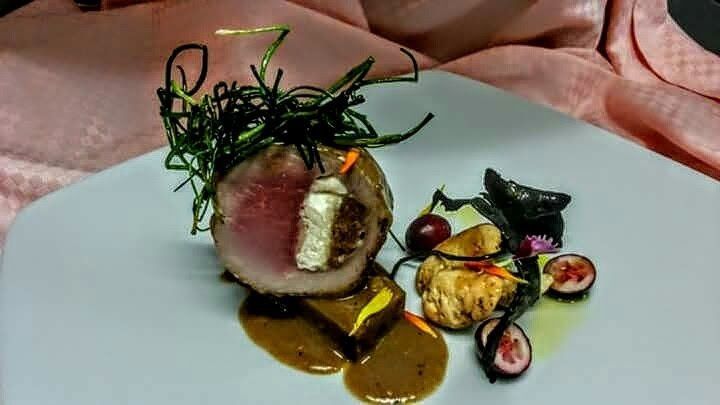 Un plato blanco cubierto con carne y verduras sobre una mesa.