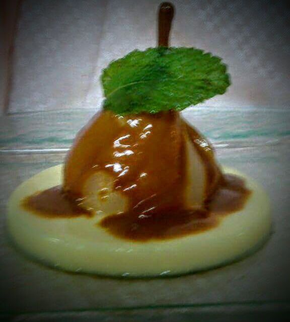 Una pera con salsa de caramelo y una hoja de menta encima.